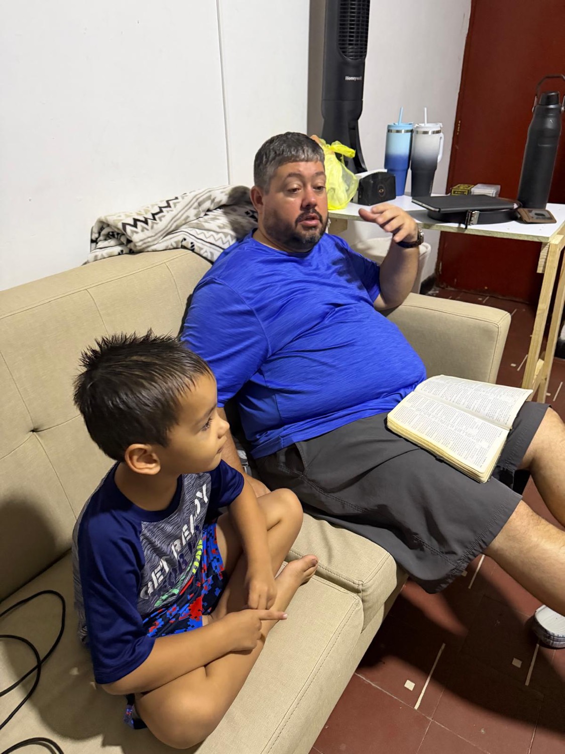 Dad reading the Bible with one of the boys on the couch
